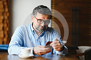 man in casual form using mobile phone at the cafe