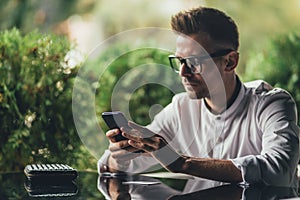 Man in casual form using mobile phone at the cafe. side view