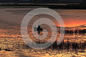 A man catches fish on an inflatable boat on the river in the evening with the setting sun. A beautiful evening in nature to relax