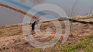 Man catches snakes in the dry grass on the riverbank.