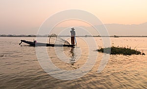 A man catching fish at sunrise on the lake in Inlay, Myanmar