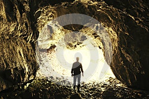 Man at cave entrance with bright light