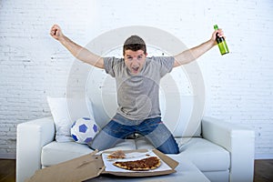 Man celebrating goal at home couch watching football game on television