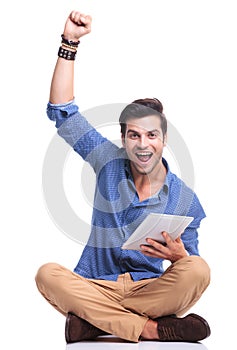 Man celebrating success while working on tablet