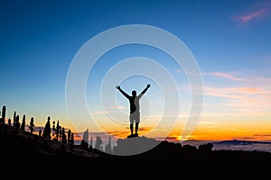 Man celebrating sunset with arms outstretched in mountains photo