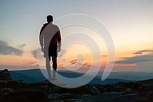 Man celebrating sunset looking at view in mountains