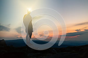 Man celebrating sunset looking at view in mountains