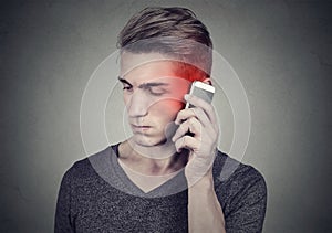 Man on the cellphone with headache. Upset unhappy guy talking on a phone