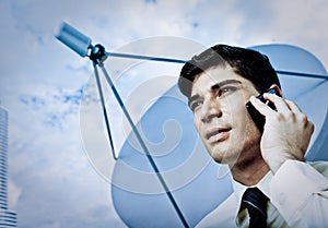 Man on cellphone by satellite dish