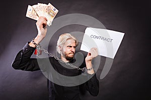 Man with chained hands holding contract and money