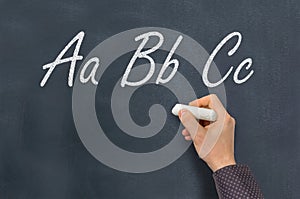 Man with chalk writing ABC letters on blackboard