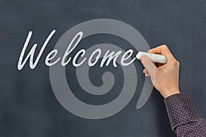 Man with chalk writing Welcome on blackboard