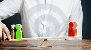 A man changes the balance of scales in favor of a green group of people. Mediator services. Conflict, dispute resolution, judicial