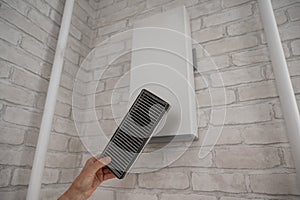 A man changes the filter at the supply ventilation. Gadget for ventilation, disinfection and air purification of the