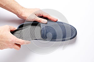 A man changes the insole in his shoes. White background, closeup.