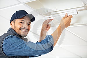 man changes neon light bulb