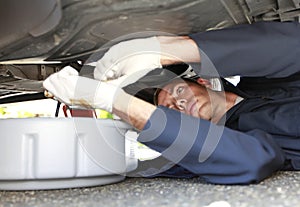 Man changing car oil laying under vehicle.