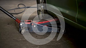 Man changing car tires in garage because of winter season. Workplace environment in dark colors, fitting the tire on rim