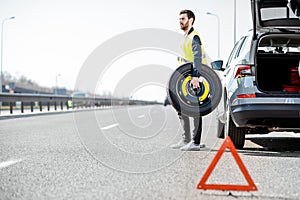 Man changing car wheel on the roadside