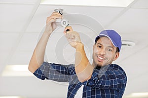 man changing ceiling light bulb