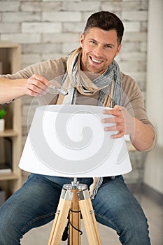 man changing light bulb on floor lamp