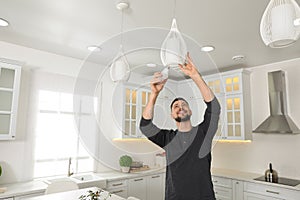 Man changing light bulb in lamp at home. Space for text