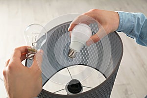 Man changing light bulb in lamp indoors