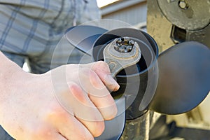 Man changing propeller on outboard motor. Repairing outboard motor for boat, replacing screw.