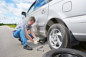 Man changing a spare tire of car