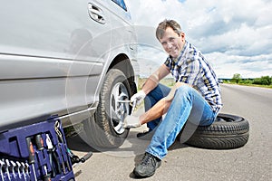 Man changing spare tire of car