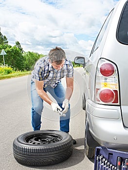 Man changing a spare tire of car