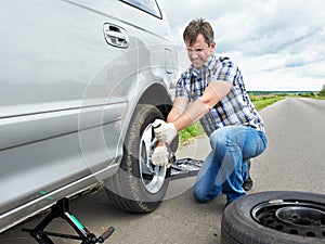 Man changing a spare tire of car