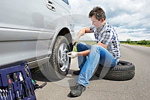 Man changing spare tire of car