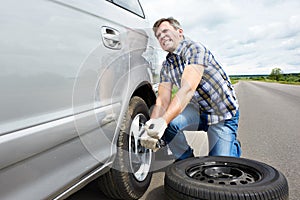 Man changing a spare tire of car