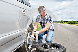 Man changing a spare tire of car