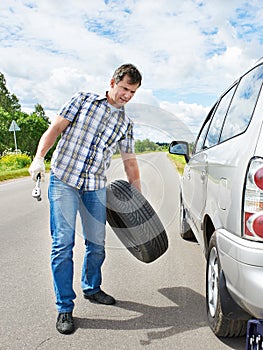 Man changing a spare tire of car