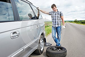 Man changing a spare tire of car