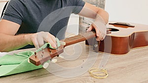 Man changing the strings of a guitar at home. Cleaning guitar