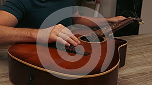 Man changing the strings of a guitar at home. Man's hand are installing or replacing strings on a classical guitar