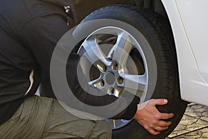 Man is changing a wheel in a car