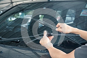 Man is changing windscreen wipers on a car