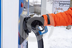 man charging electric car, holding DC charging connector in hand, ev Combined Charging System CCS2 quick-charge station,