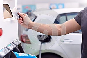 Man Charging Electric Vehicle Paying For Energy With Credit Card At Charging Station