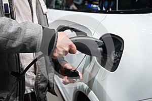 Man charging electro car. Man holding in hand power cable supply ready to plugged in into charging port