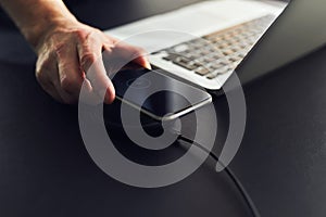 Man charging mobile phone on wireless charger