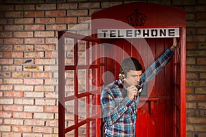 Man chatting inside a red telephone booth