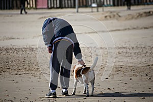 Old man pets a dog at a British beah photo