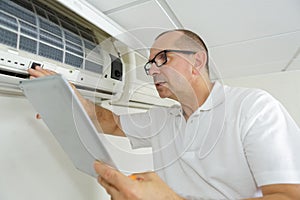 Man checking airconditioning manual while using it