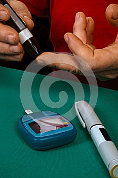 Man checking blood glucose level using lancing device and glucose meter