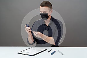 Man checking blood sugar level with glucometer on gray background